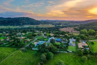 Vista aérea ampla mostrando o condomínio e colinas verdes