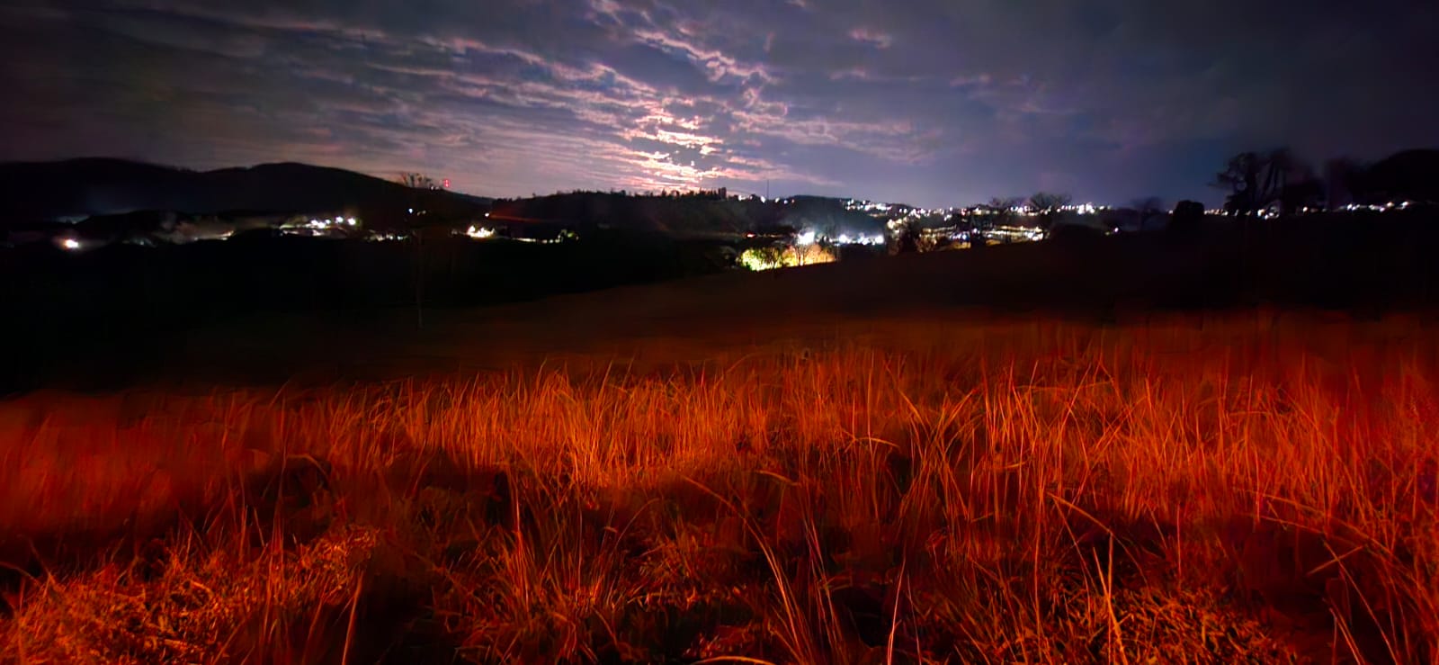 Vista noturna panorâmica com luzes da cidade e céu estrelado